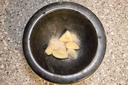 Chop garlic cloves and put into mortar